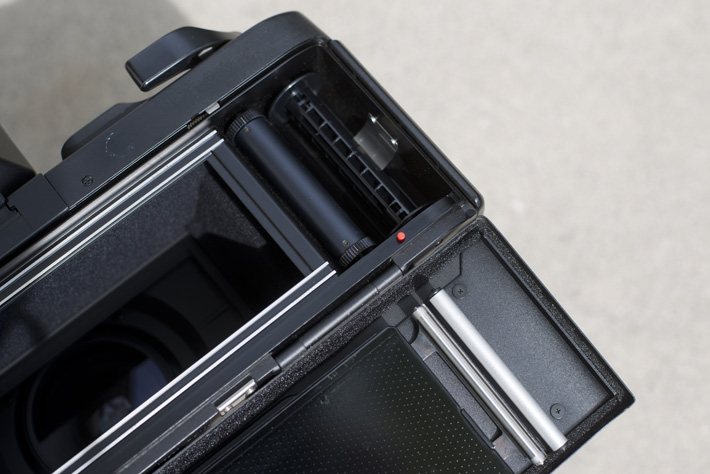 That little red button unlocks the pin for the 120 film reel so you can take it out. A larger pin on the bottom of the camera locks the pin back in place.