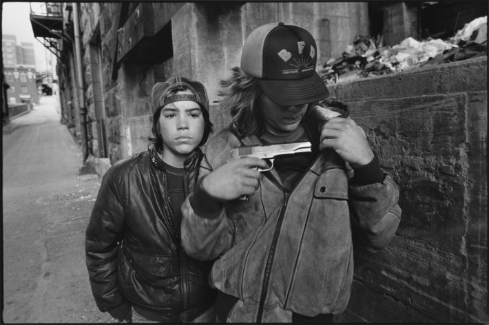 Image name: ‘Rat’ and Mike with a Gun, Seattle, Washington 1983 Streetwise Copyright: @Mary Ellen Mark