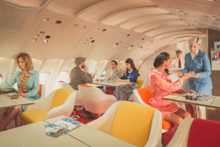 After dinner, passengers are free to roam around the plane. Many take to the upstairs lounge - a signature feature of Pan Am's 747 fleet - where they can relax with drinks, cigarettes, table games and enjoy conversations with fellow travelers while enjoying the view of the sun skipping across the horizon at 35,000 feet.